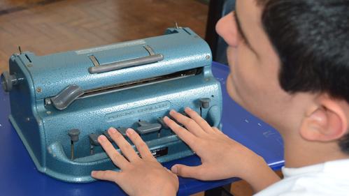 O estudante Rafael Dias Antunes usa a máquina de escrever braille