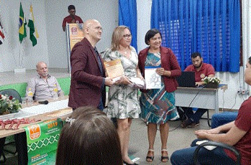 Professores premiados recebendo diplomas e livros